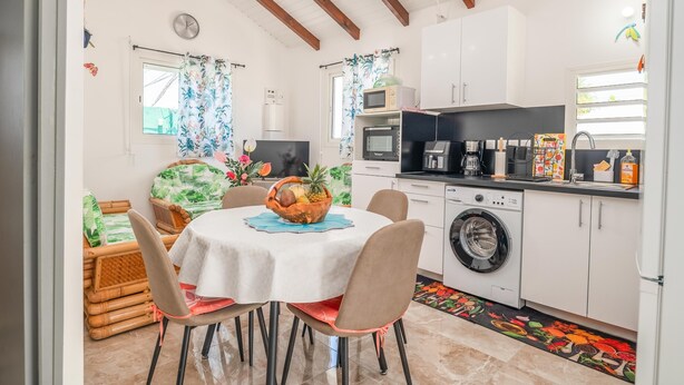 Una cucina compatta con lavatrice, forno a microonde e zona pranzo con tavolo e sedie.