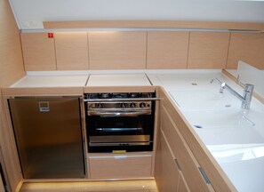 Eine kleine Küche mit Einbauofen, Spüle und einem Kühlschrank.