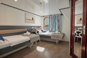 Ein Hotelzimmer mit zwei Betten, einem Schreibtisch, einem Stuhl, einem Fenster mit Vorhängen und einer Deckenleuchte.