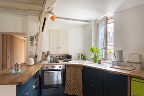 A kitchen with a wooden countertop, a stove, a sink, and a window with a view. - Ty Michel - Au centre-ville de Rennes (Rennes)