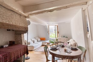 A cozy room with a dining table set for four, a sofa, a small table with a plant, and a window with a view. - Ty Michel - Au centre-ville de Rennes (Rennes)