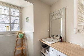 A bathroom with a window, a wooden chair, a sink, and a mirror. - Ty Michel - Au centre-ville de Rennes (Rennes)