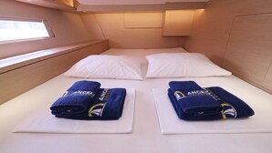A compact cabin with a bunk bed, two towels with a logo, and a window providing natural light. - Sun-Kissed Sailing Adventure in Zadar, Croatia (Biograd na moru)