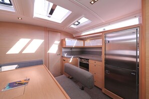 Una cocina compacta con horno integrado, un refrigerador y una bancada.