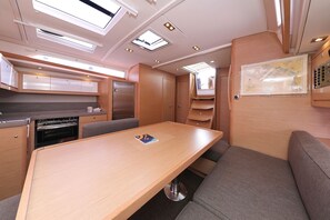 A compact kitchen with a built-in oven, a dining table with a map, and a seating area with cushioned benches. - Sun-Kissed Sailing Adventure in Zadar, Croatia (Biograd na moru)