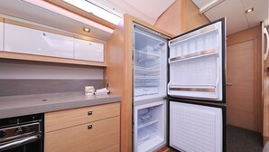A compact kitchen with a built-in oven, a refrigerator with a freezer, and a microwave. - Sun-Kissed Sailing Adventure in Zadar, Croatia (Biograd na moru)