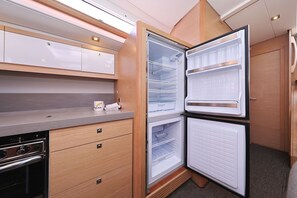 Eine kompakte Küche mit Einbauofen, Kühlschrank mit Gefrierfach und Mikrowelle.