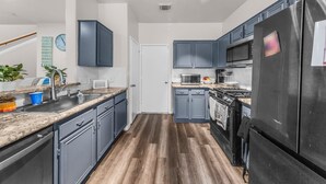 Une cuisine avec des meubles de couleur bleu foncé, un réfrigérateur en acier inoxydable, un four à micro-ondes et une cuisinière.