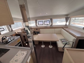 A compact kitchen with a stove, a dining table, and a built-in bench. - Sun-Kissed Sailing Adventure in the Sporades Islands from Volos, Thessaly (Volos)
