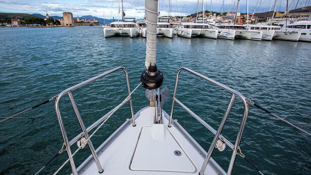 A boat's deck with metal railings, a mast, and a view of a marina with boats and a distant castle. - Sun-Kissed Sailing Adventure in Zadar, Croatia (Zadar)