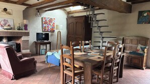 Een rustieke eethoek met een houten tafel, stoelen en een open haard.