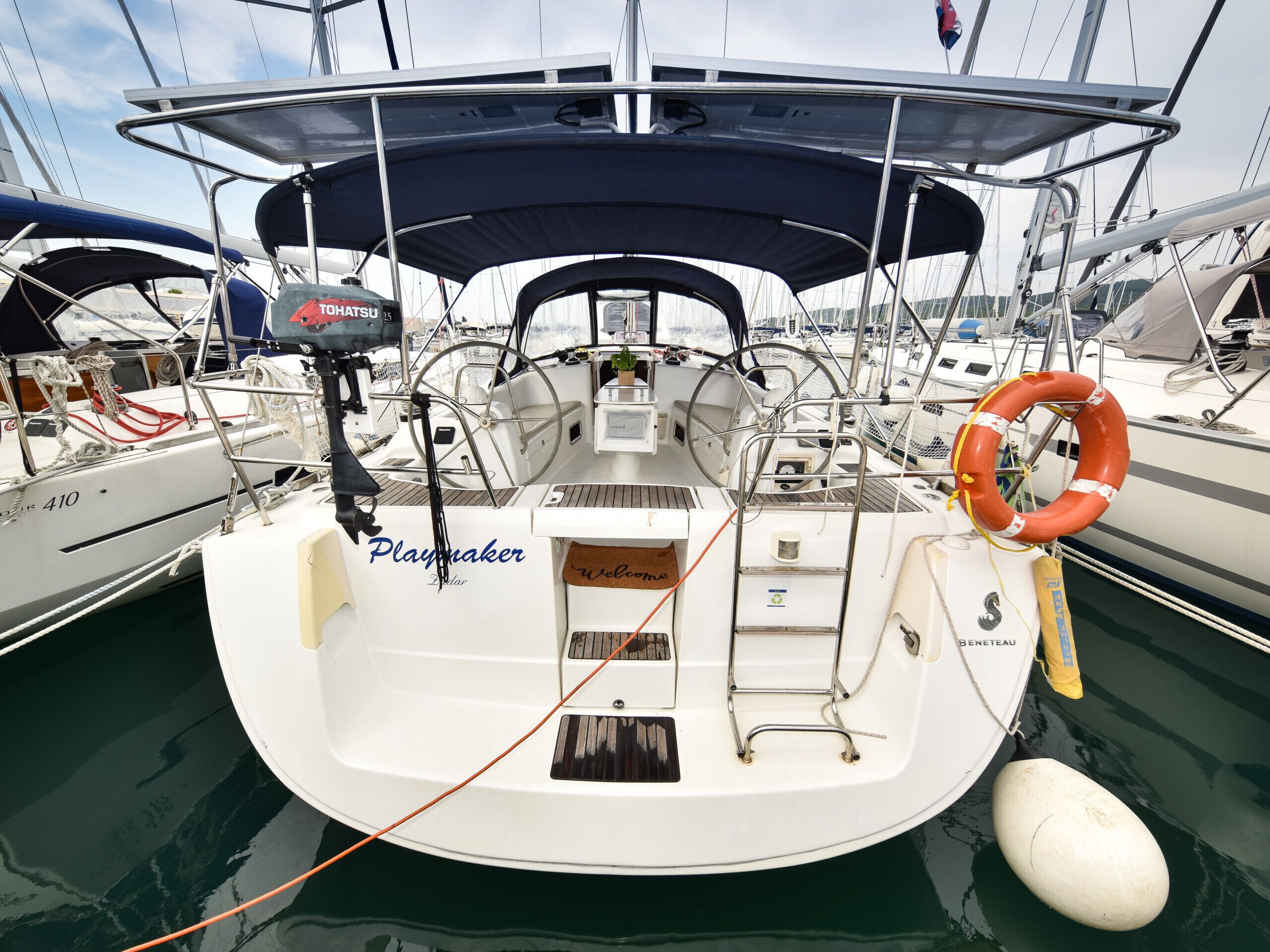 A boat deck with a Playmaker steering wheel, a life buoy, and a 'Welcome' sign.
