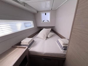 Ein gemütliches, helles Blockhaus mit einem Einzelbett, einem kleinen Fenster und einer integrierten Sitzbank.