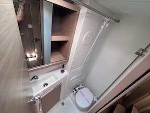 Ein kleines Badezimmer mit Waschbecken, Spiegel und Toilette.