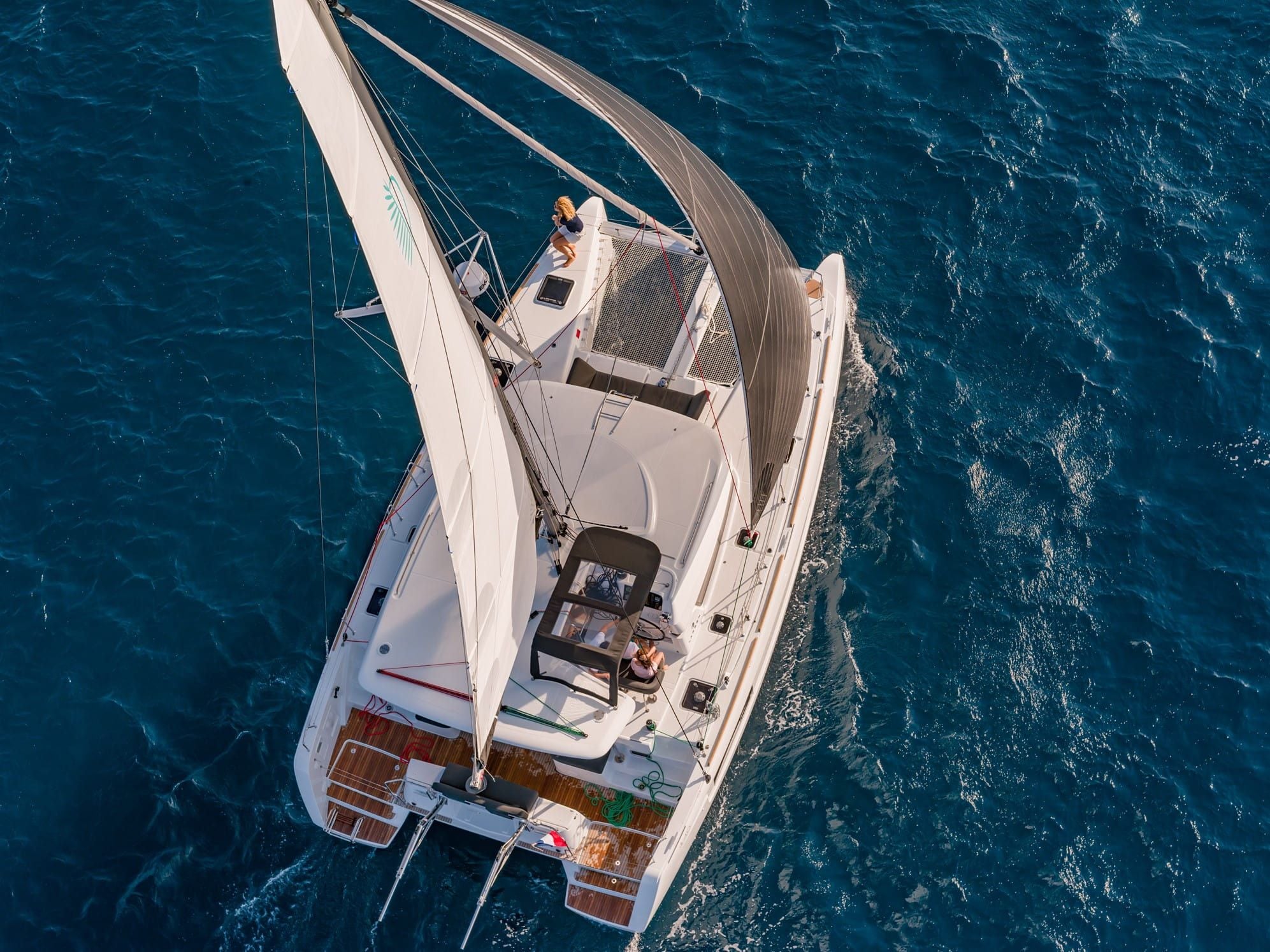 A high-angle view of a sailboat with a cabin, deck, and a person on the bow.
