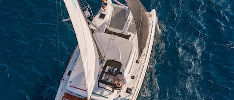 A high-angle view of a sailboat with a cabin, deck, and a person on the bow.
