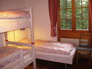 A bunk bed room with a window and a chair.