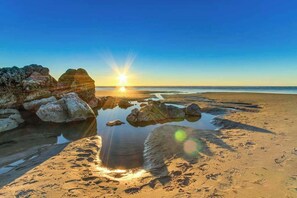 Ein Strand mit Felsen und blauem Himmel.