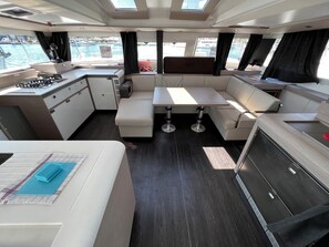 Un intérieur compact comprenant une kitchenette, un coin salon et une vue sur le port de plaisance.