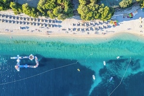 An aerial view of a beach with clear turquoise waters, a pier, and several boats. - Sun-Kissed Sailing Adventure in Sibenik, Croatia (Primošten)