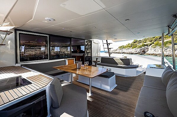 A yacht's interior with a dining area, seating, and a view of the sea.