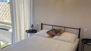 Una camera da letto con un letto, un comodino, una lampada a parete e vista sull'esterno.