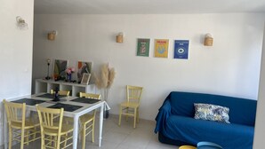 Zona pranzo con tavolo e sedie, un divano blu e decorazioni a parete.