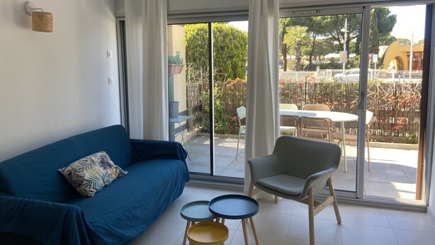 Un soggiorno moderno con un divano blu, una poltrona grigia e due tavolini.