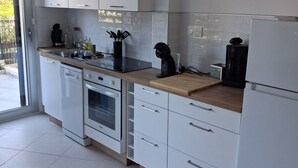 Una cucina moderna con mobili bianchi, lavastoviglie, forno, macchina del caffè e frigorifero.