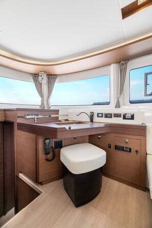 A compact galley with a sink, a telephone, and a small stool. - Sun-Kissed Sailing Adventure in Islas Sarónicas (Piraeus)