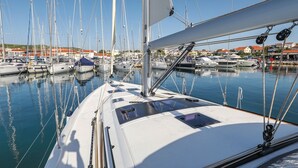 Eine Marina mit mehreren Segelbooten an den Liegeplätzen, wolkenloser Himmel und Gebäuden im Hintergrund.