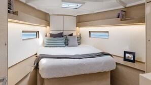 Une chambre à coucher de taille réduite, comprenant un lit, des tables de chevet et une fenêtre.