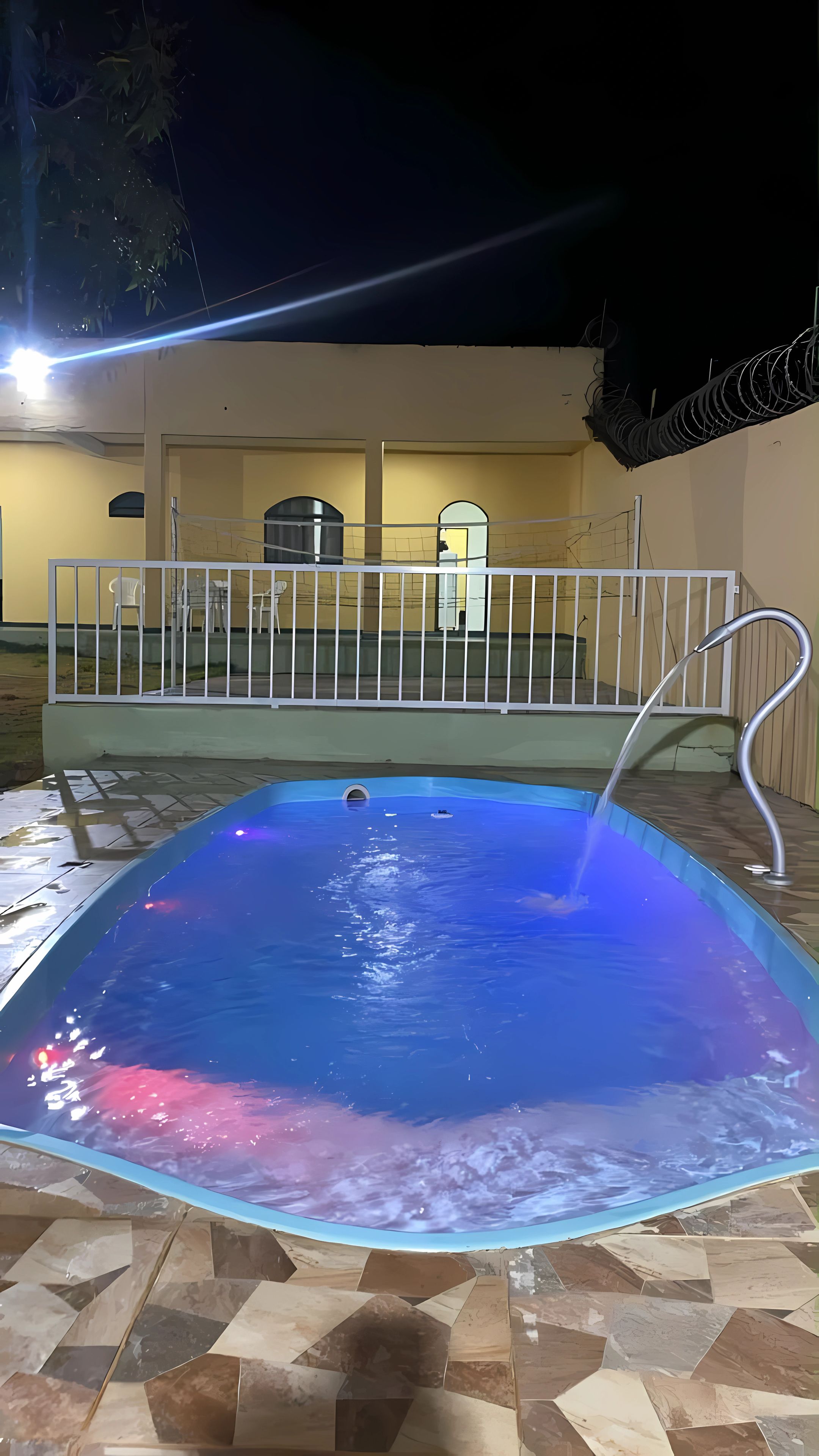 A swimming pool with a metal ladder and a white fence.