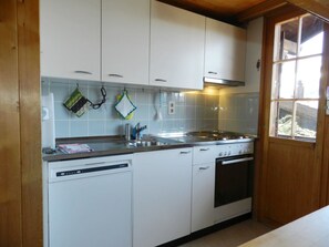 A kitchen with white cabinets, a dishwasher, and a stove. - Guex Appartement/Fewo, Dusche oder Bad, WC 5-Bettwohnung by Interhome (Gstaad)
