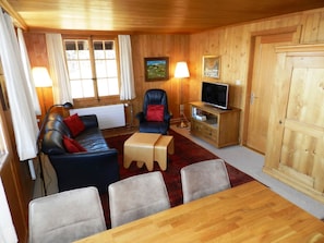 Een knus interieur met een bank, stoelen, een televisie en een houten kast.