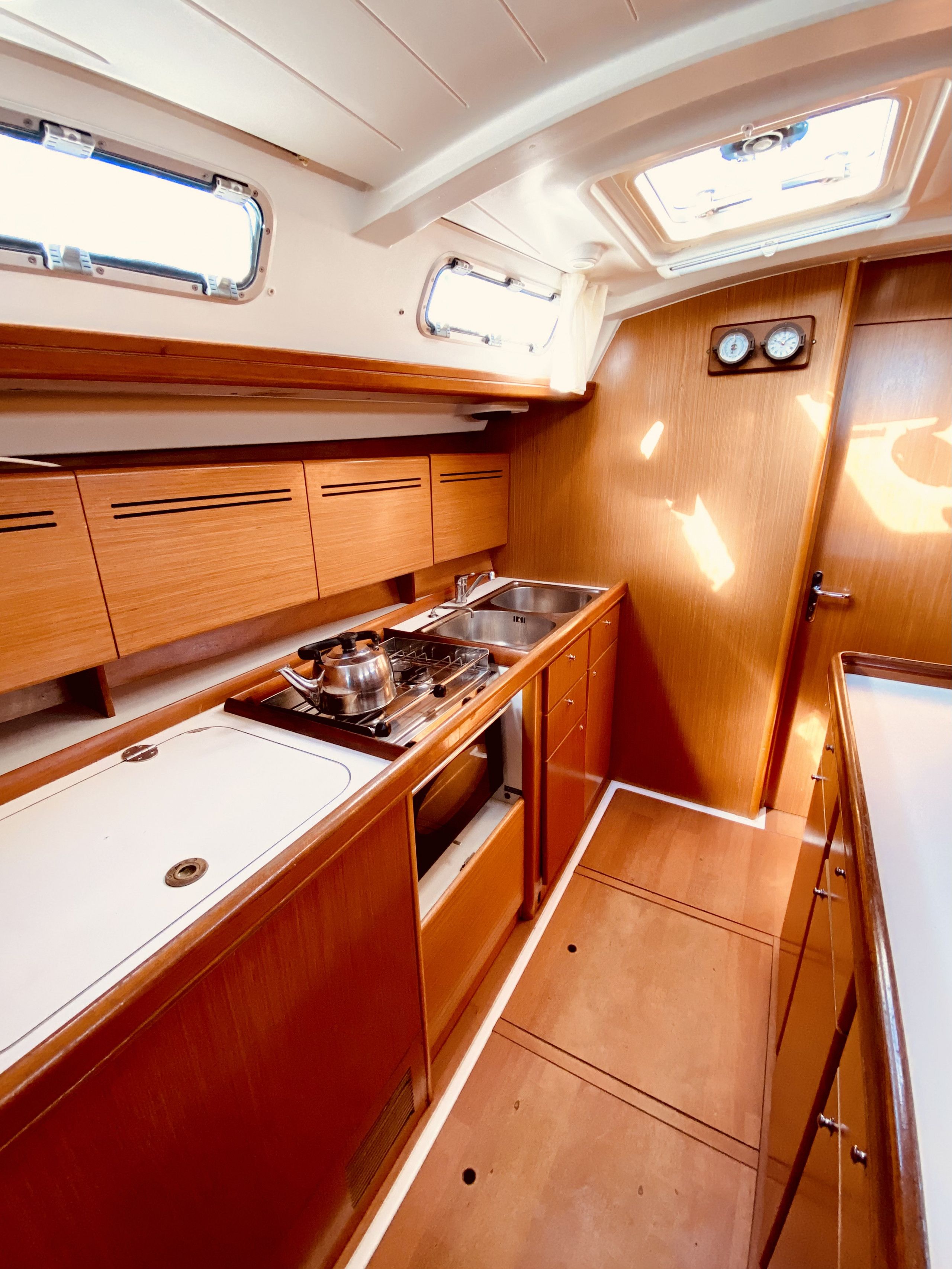 A compact galley with wooden cabinetry, a stainless steel sink, and a stove.