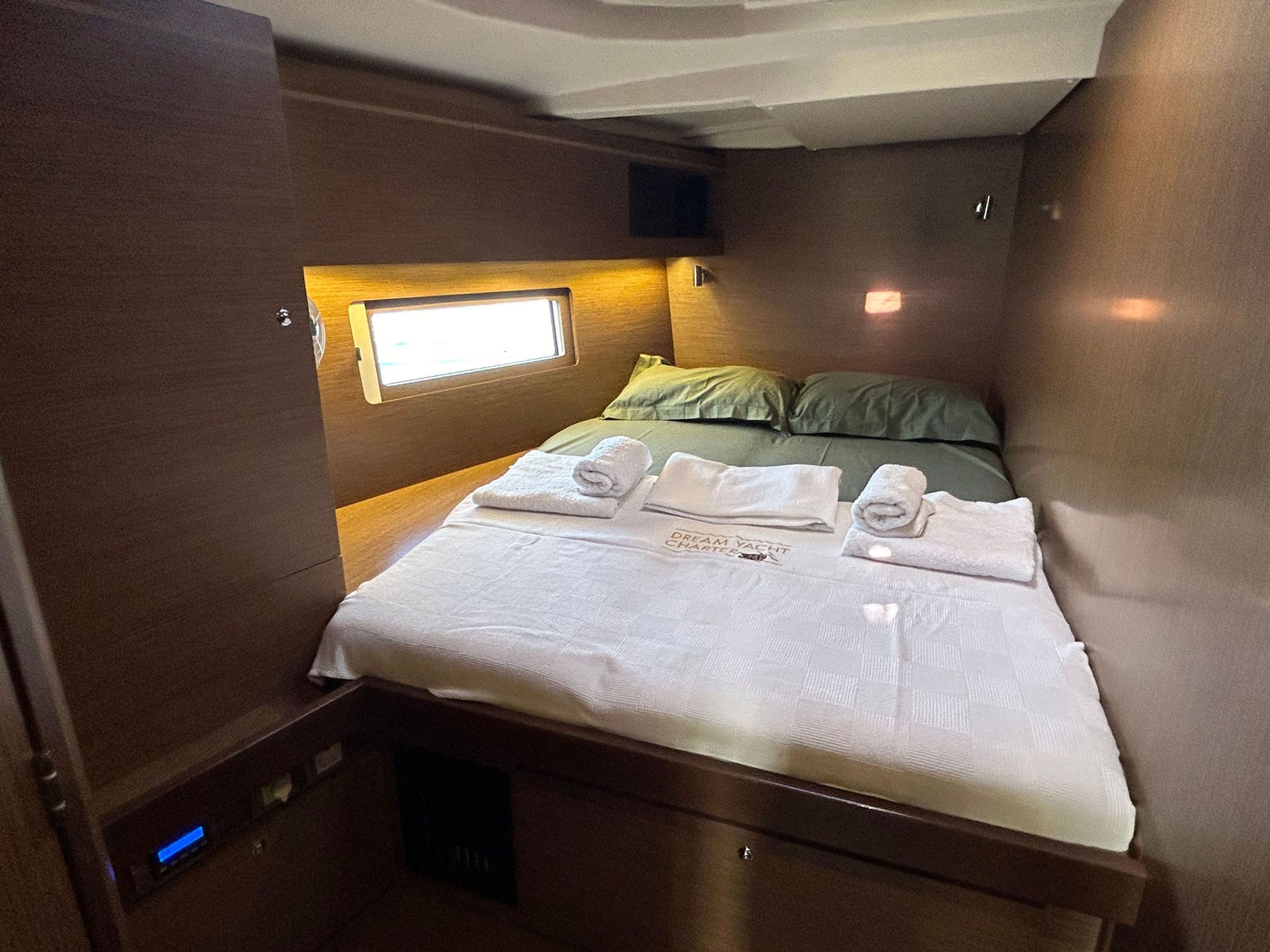 Un dormitorio pequeño con cama, almohadas y toallas dobladas con esmero.