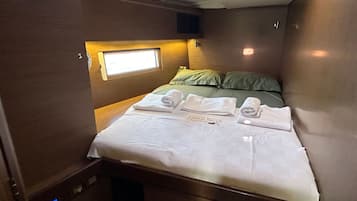 Un dormitorio pequeño con cama, almohadas y toallas dobladas con esmero.