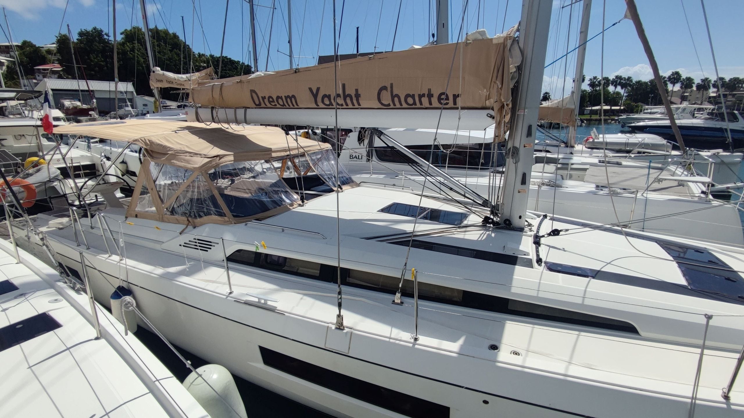 Eine Yacht mit dem Namen 'Dream Yacht Charter' liegt in einer Marina zusammen mit anderen Booten vor Anker.