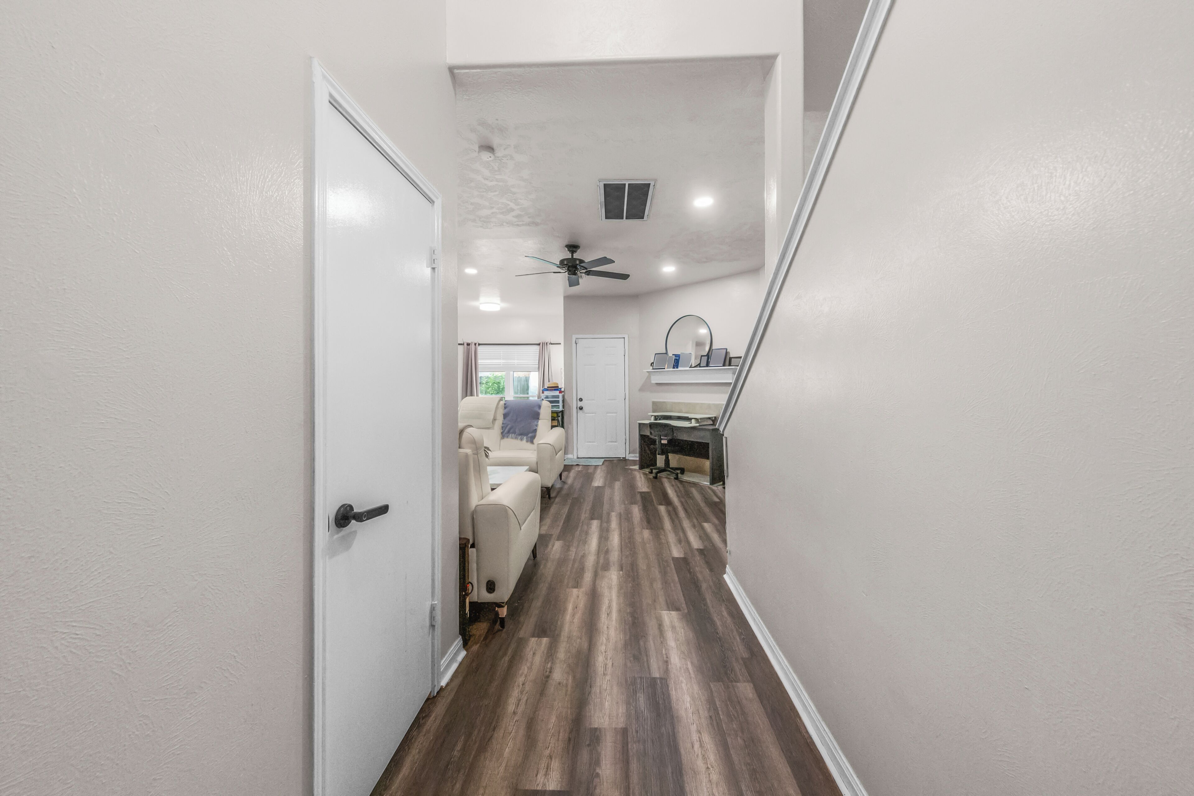 A hallway with a ceiling fan, a door, and a chair.