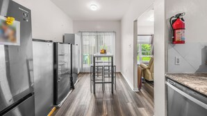Cocina moderna con electrodomésticos de acero inoxidable, un taburete de bar y un extintor.