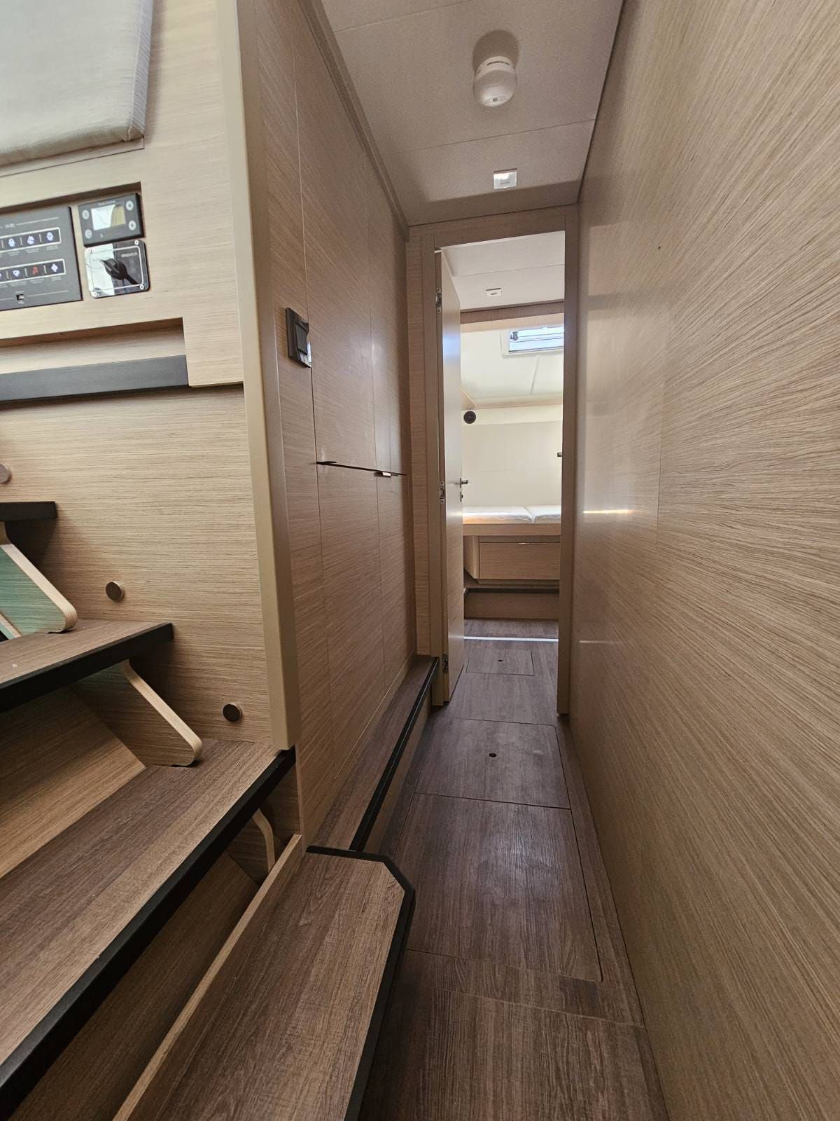 A narrow hallway with wooden walls, a bench on the left, and a door at the end.