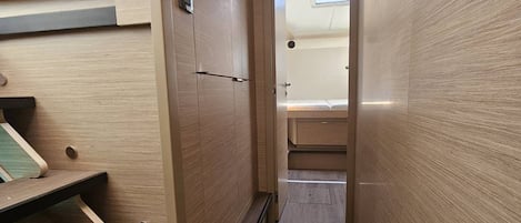 A narrow hallway with wooden walls, a bench on the left, and a door at the end.
