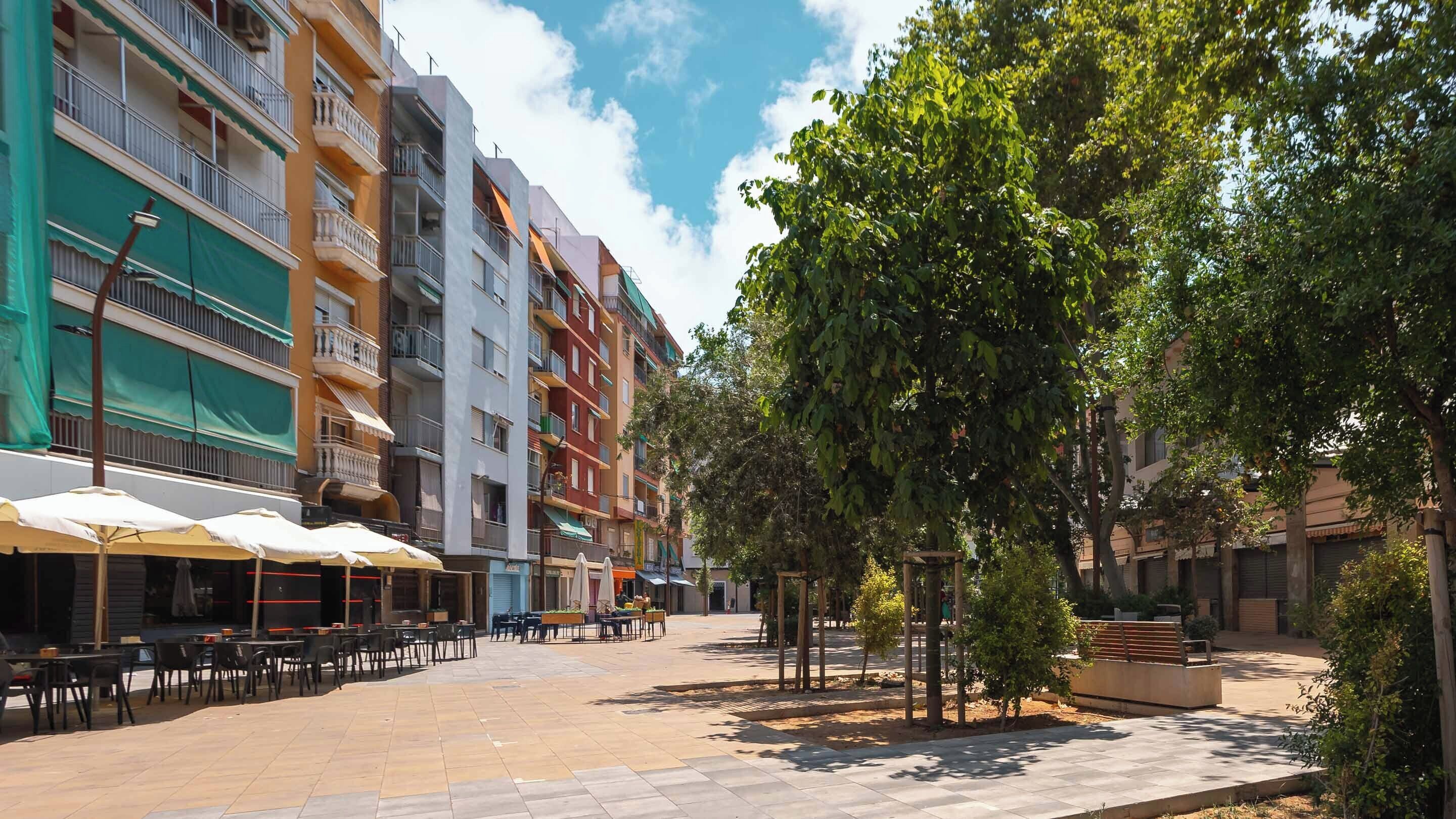 Un patio con mesas al aire libre y una hilera de edificios de varios pisos.