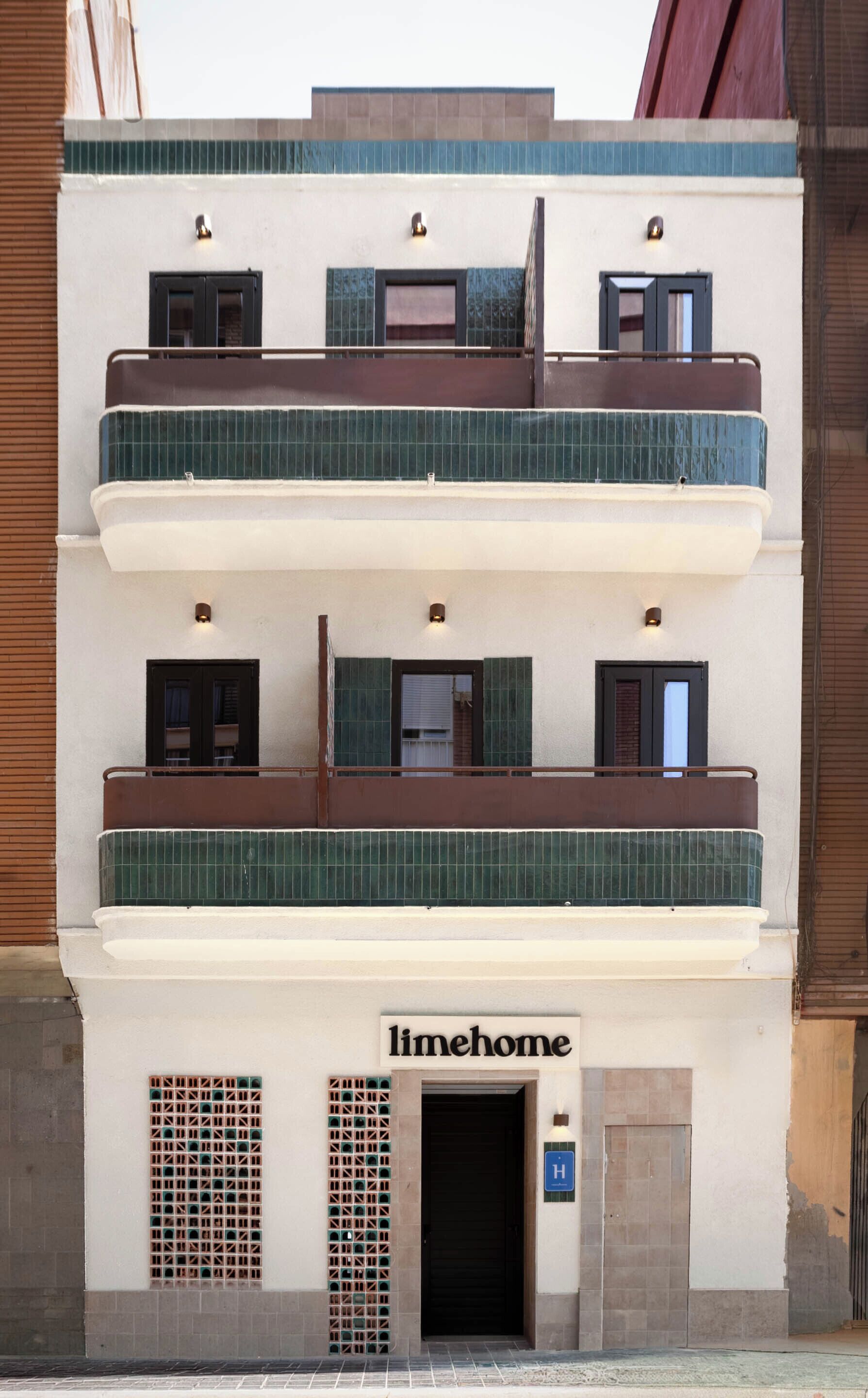 Um edifício de vários andares com uma placa indicando 'limehome' e uma entrada visível.