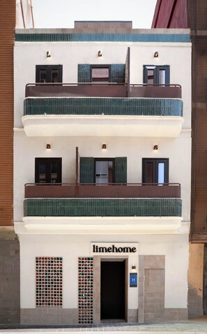 Ein mehrstöckiges Gebäude mit einem Schild, auf dem 'limehome' steht, und einem gut sichtbaren Eingang.