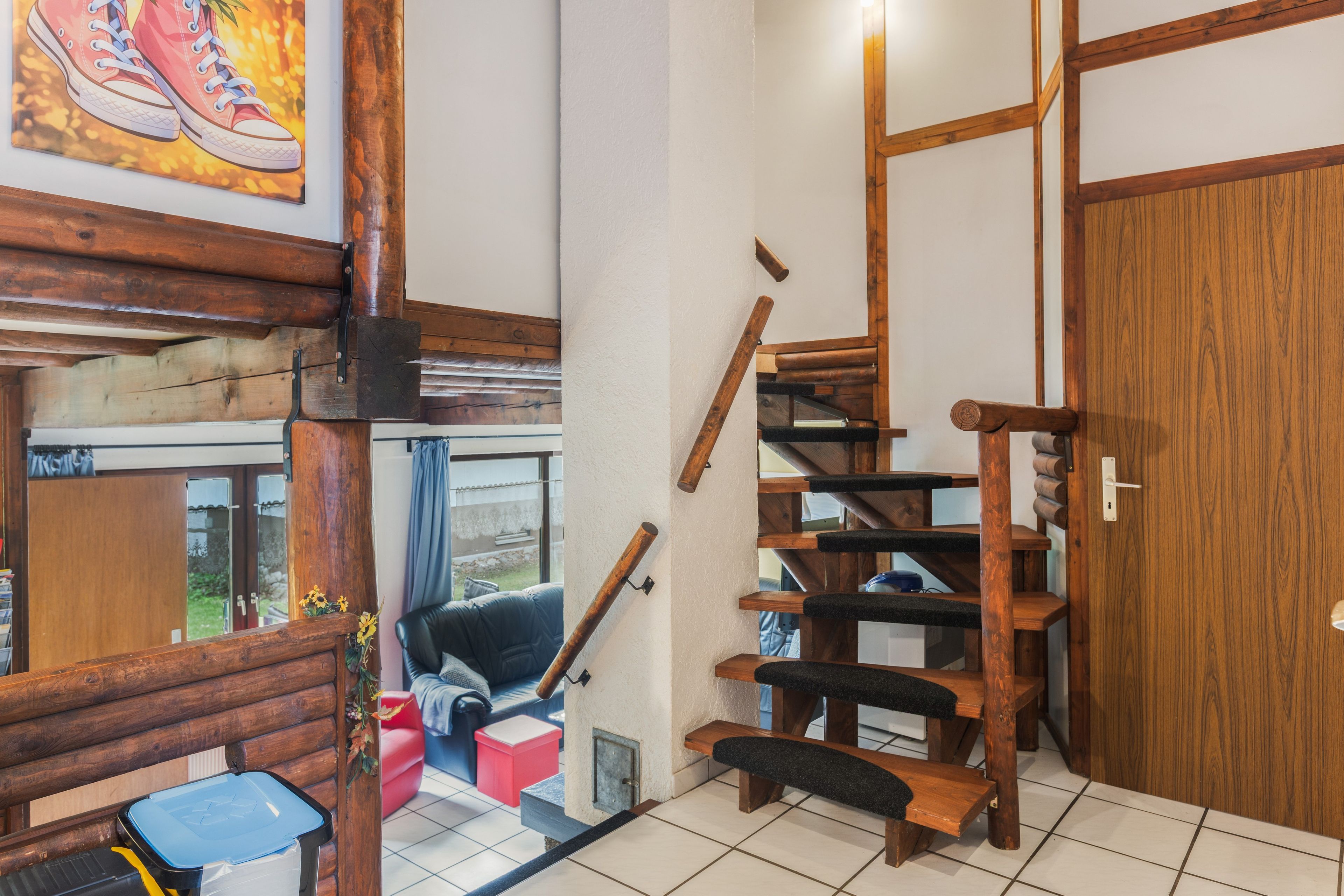 Un escalier en bois avec une rampe, une porte et une fenêtre donnant sur l’extérieur.