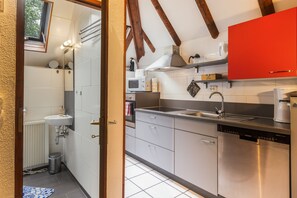 Una cocina moderna con armarios blancos, una pared de acento roja, horno empotrado y lavavajillas.
