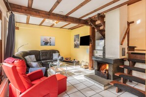A living room with a fireplace, a sofa, a red chair, and a television.