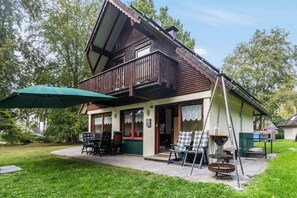 Una casa tradicional de madera con balcón, mobiliario exterior y un brasero.